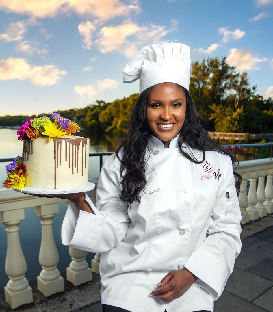 pastry chef is a woman in uniform. The pastry chef holds the cake