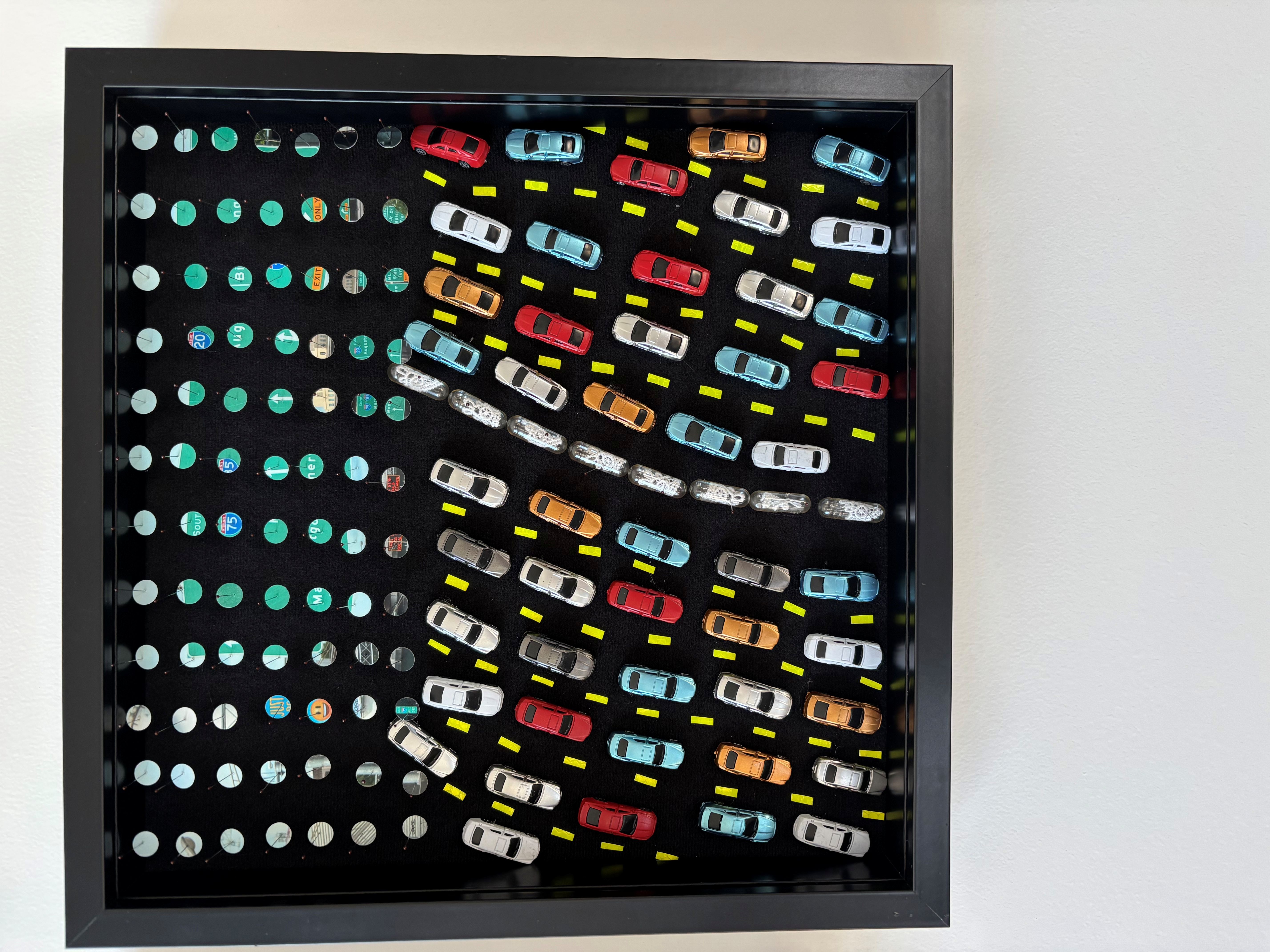 A display with colorful toy cars arranged in a pattern on a black background.