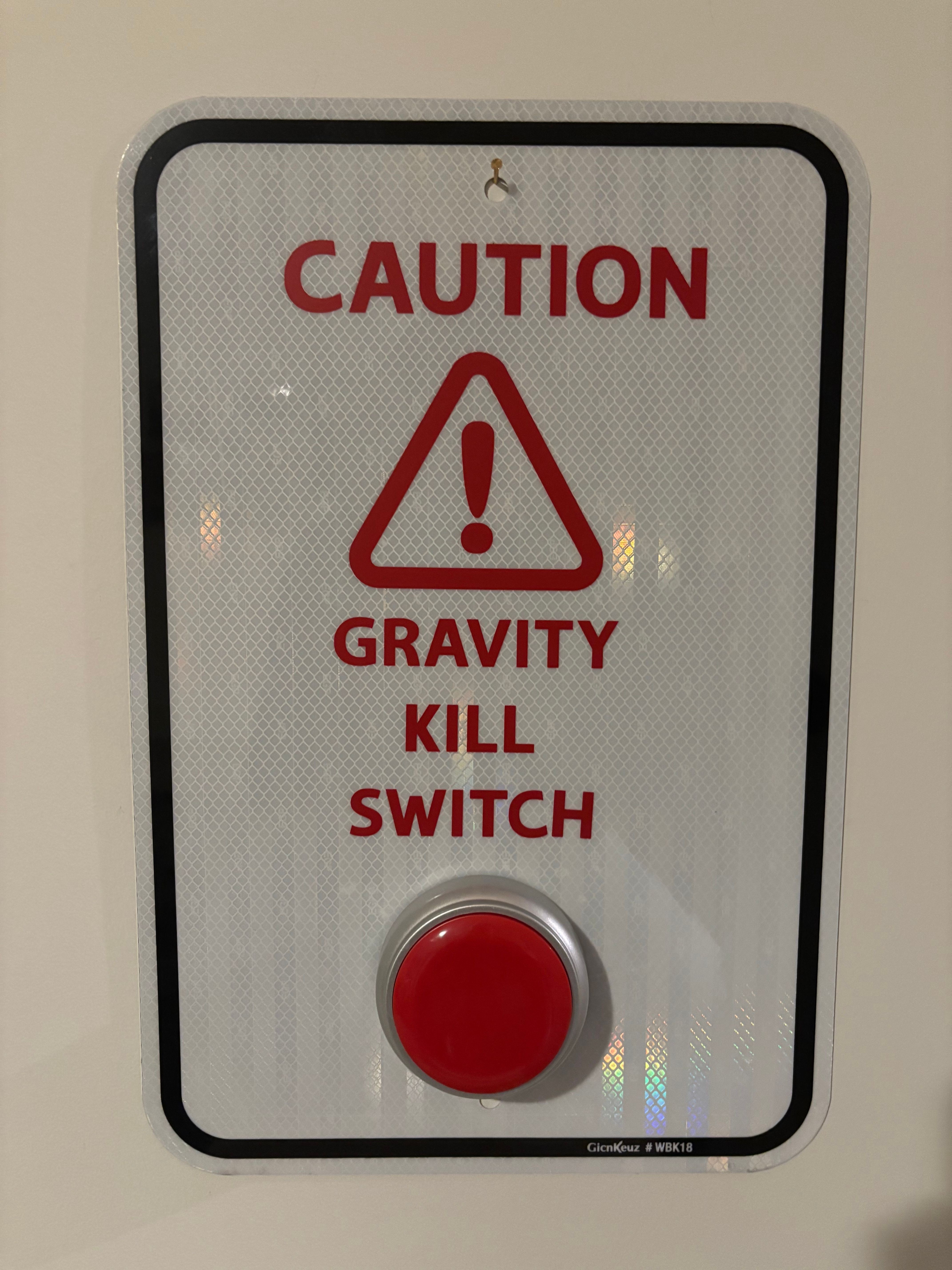 Warning sign with red text and a triangle symbol, indicating gravity kill switch, and a red button.
