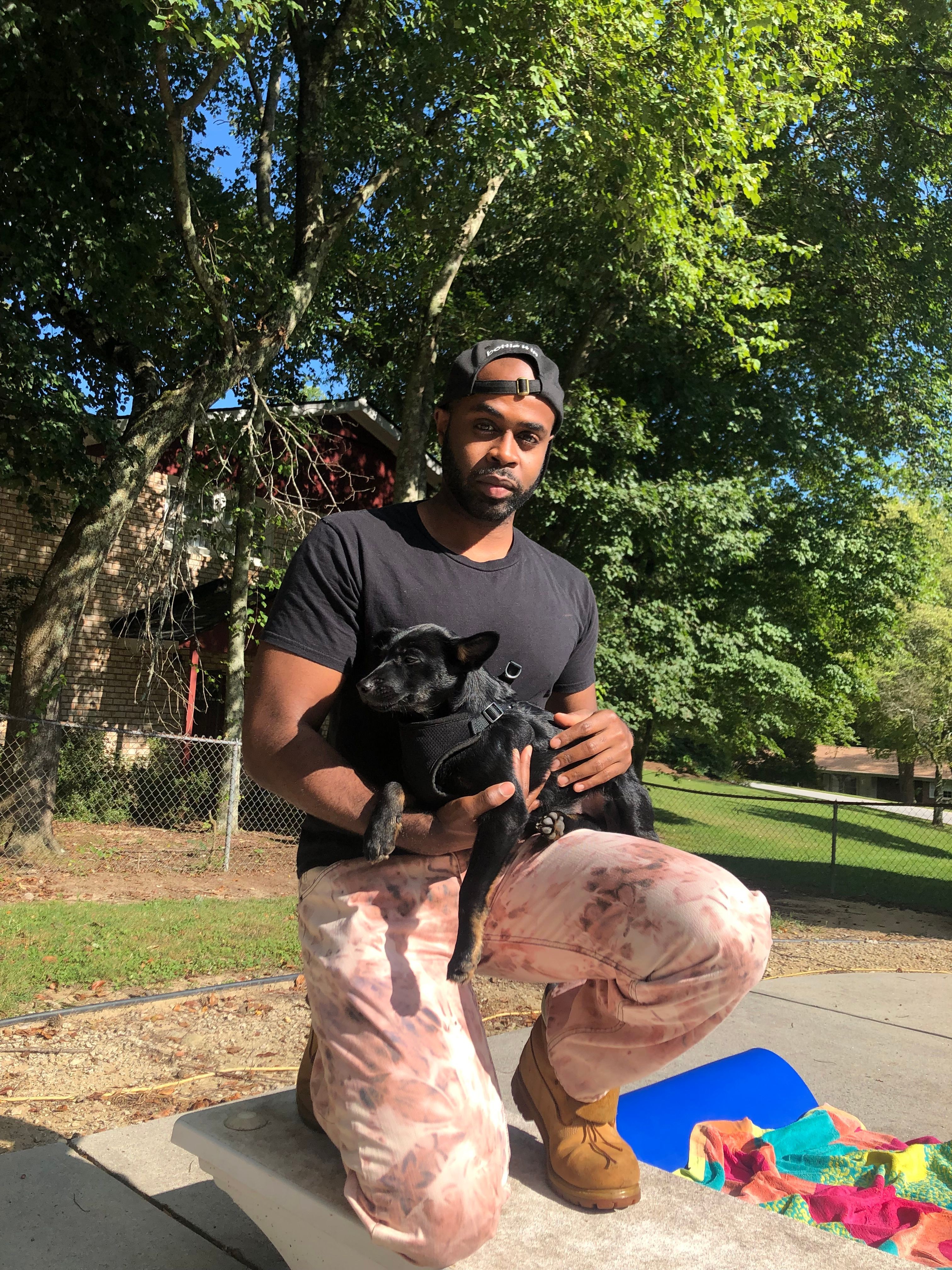Person holding a camera outdoors with trees and a park in the background.