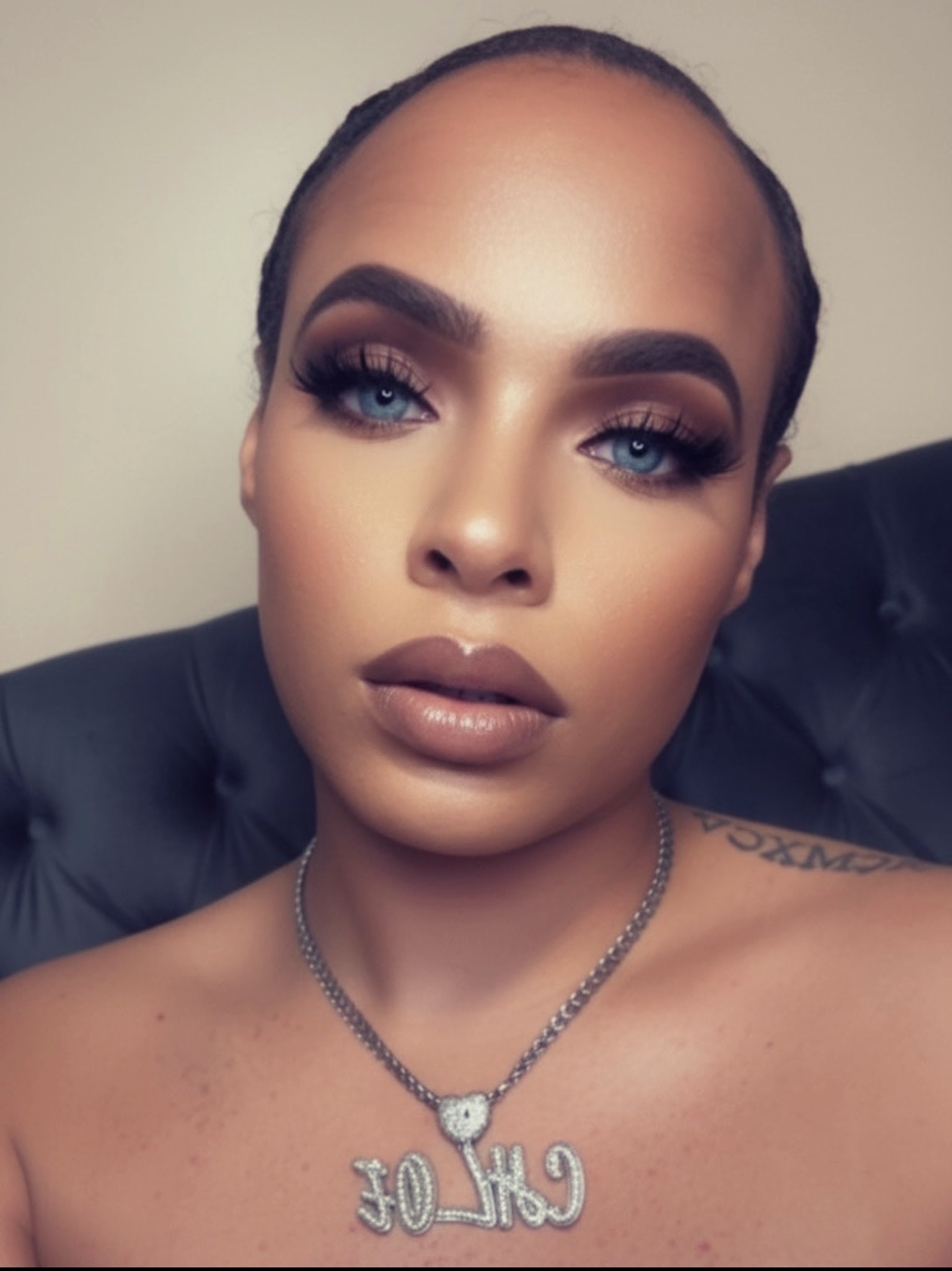 Close-up of a woman with makeup, wearing a necklace with the word 'GIRL' and a heart pendant.
