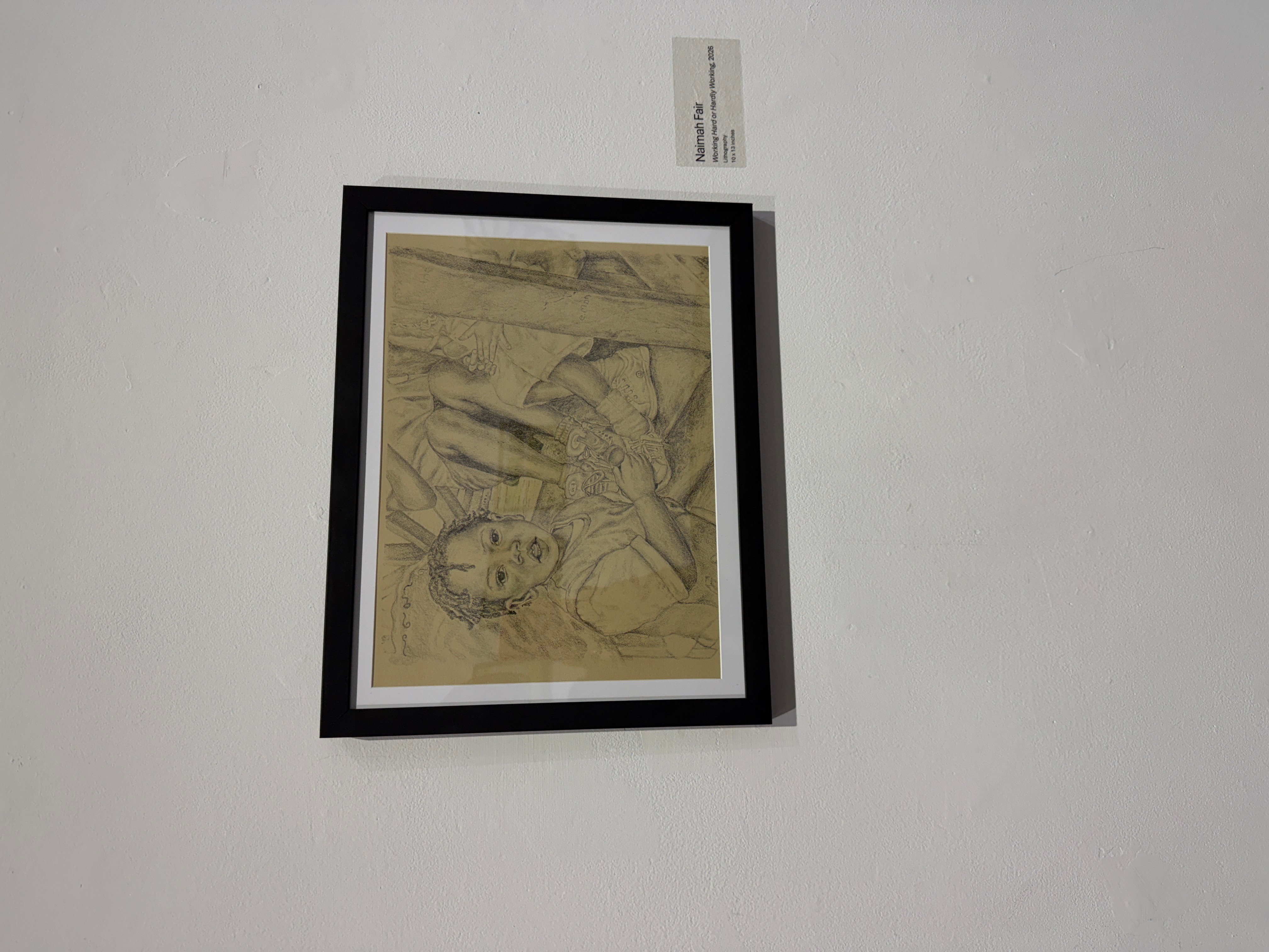 Framed artwork hanging on a white wall, with a small label above it.