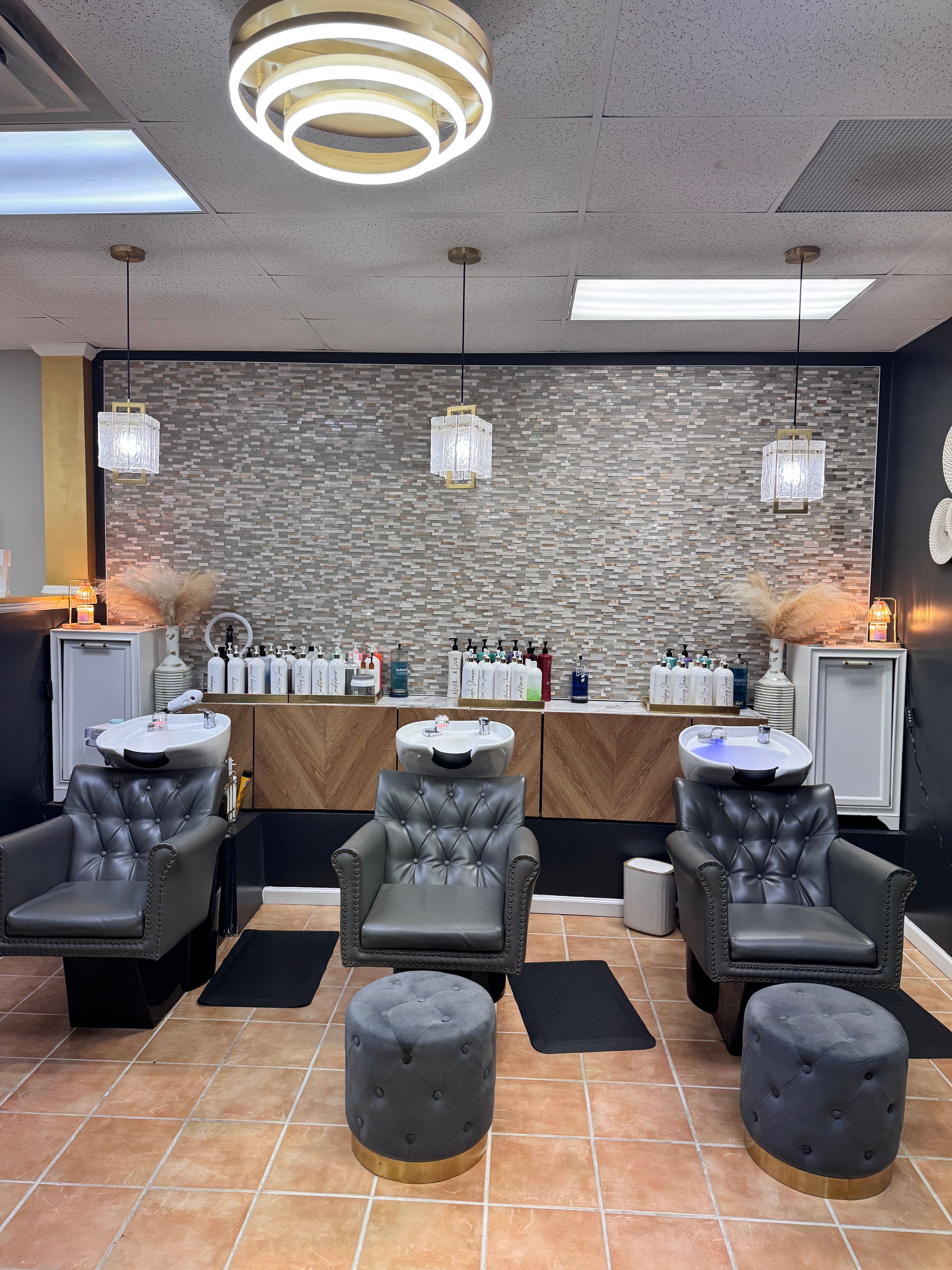 Modern waiting area with black chairs, round ottomans, and a textured wall with shelves and lighting.