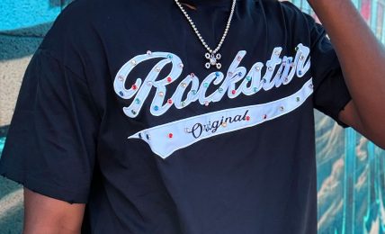 Man wearing sunglasses and a black T-shirt with 'Rockstar' text, standing in front of a colorful graffiti wall.