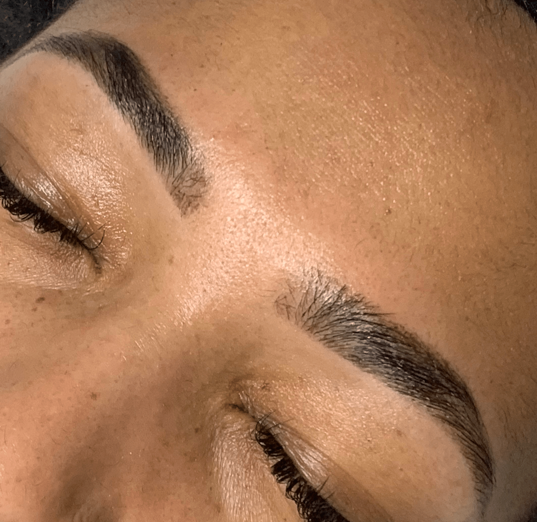 Close-up of a person's eyebrows and closed eyes, showing well-groomed eyebrows and smooth skin.