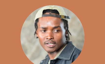 Portrait of a young man wearing a cap, looking to the side, with a neutral background.