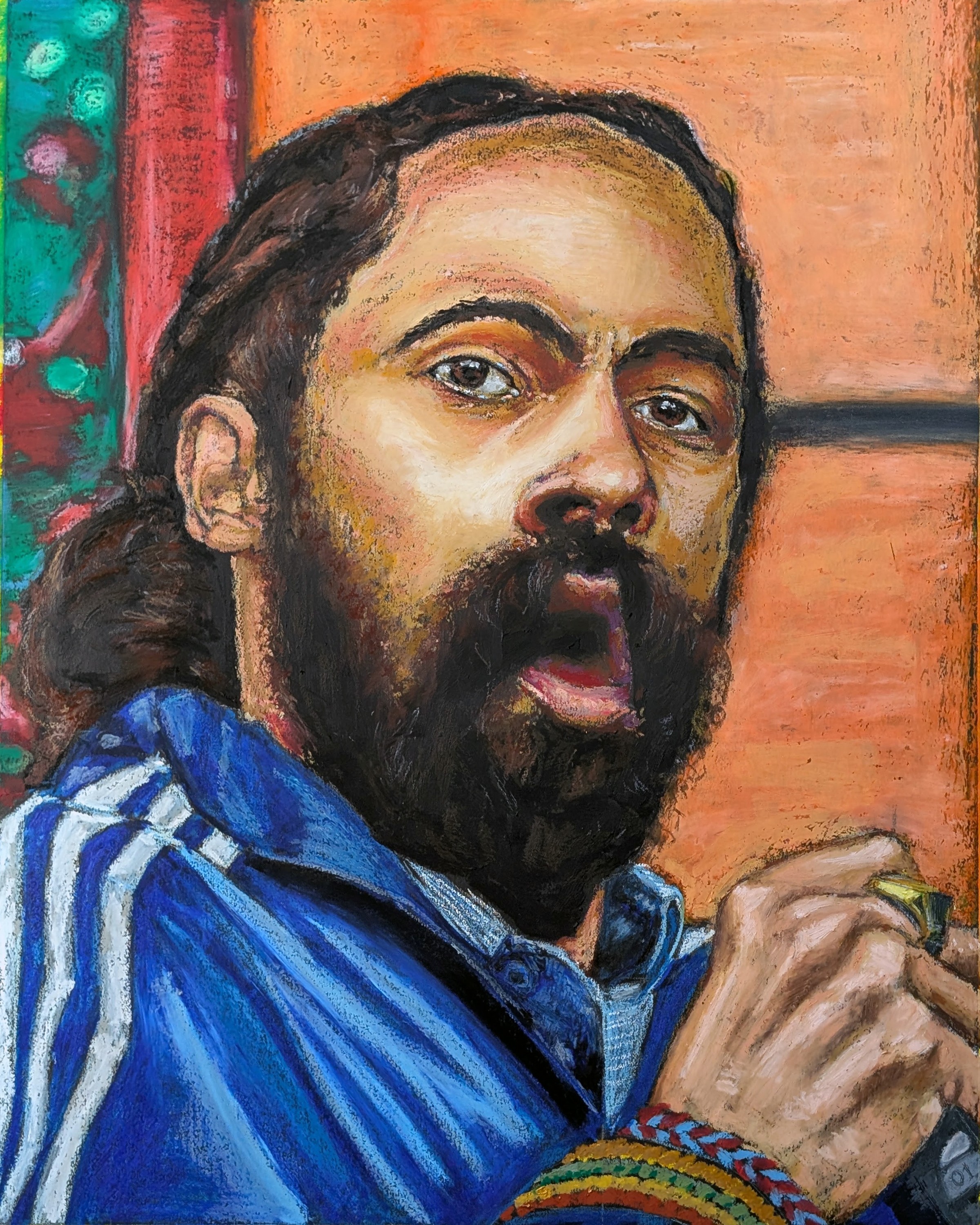 Person with long hair and beard wearing a blue jacket, holding an object, with colorful background.