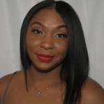 Young woman with straight black hair, red lipstick, and a necklace, smiling at the camera against a plain background.