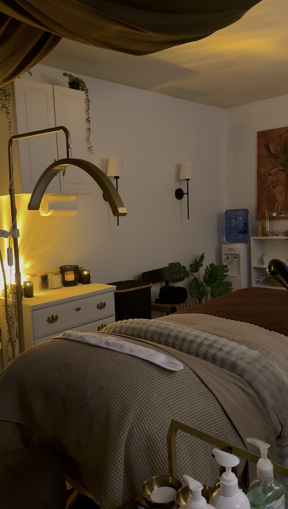 Bedroom with bed, nightstand, lamp, and wall decorations, illuminated by warm yellow lighting.