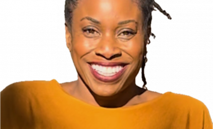 Smiling woman with braided hair wearing a mustard yellow top, facing forward, against a black background.