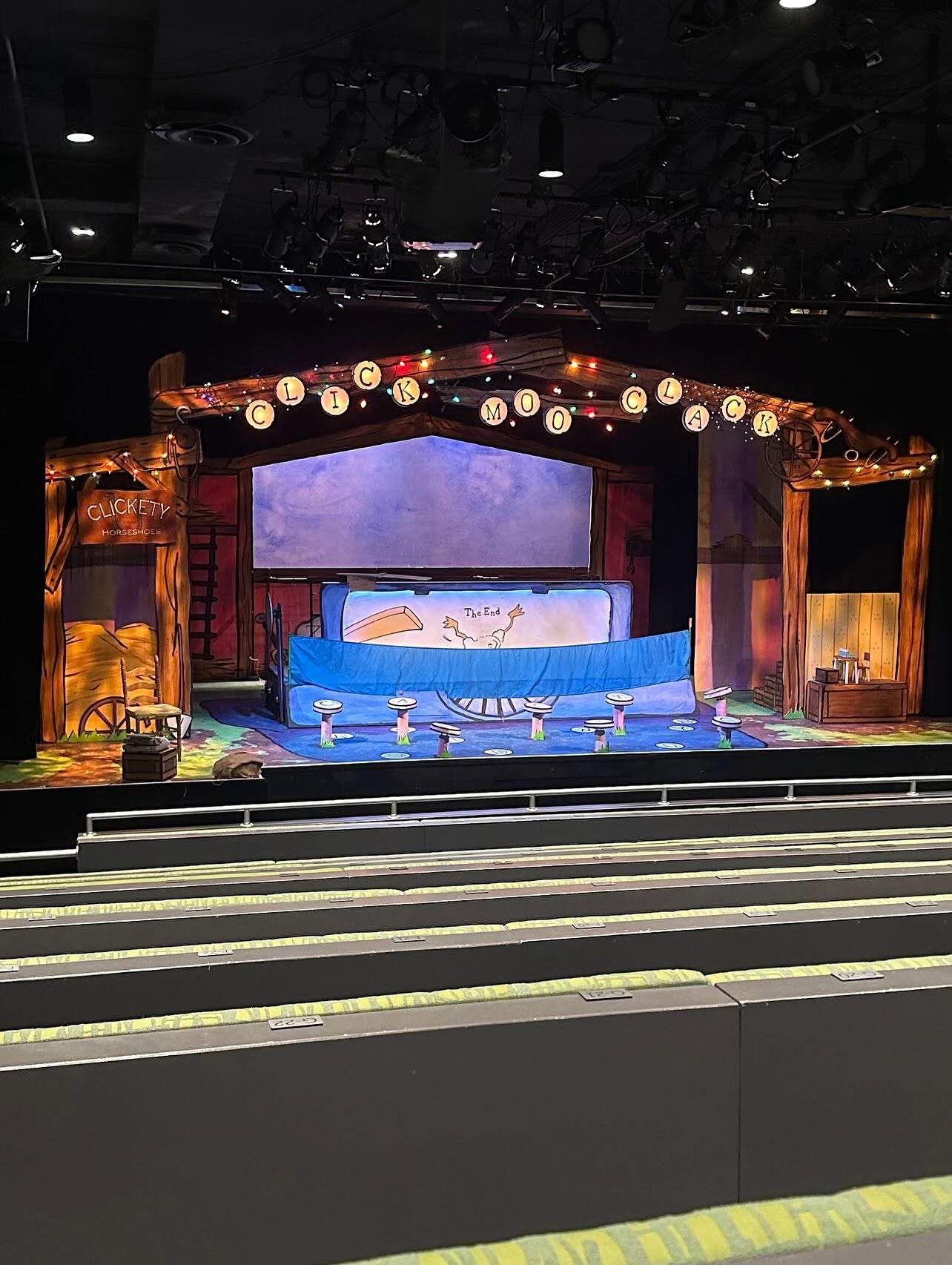 The stage is set with a blue and white backdrop, decorated with hanging lanterns and ornate wooden frames, ready for a performance.