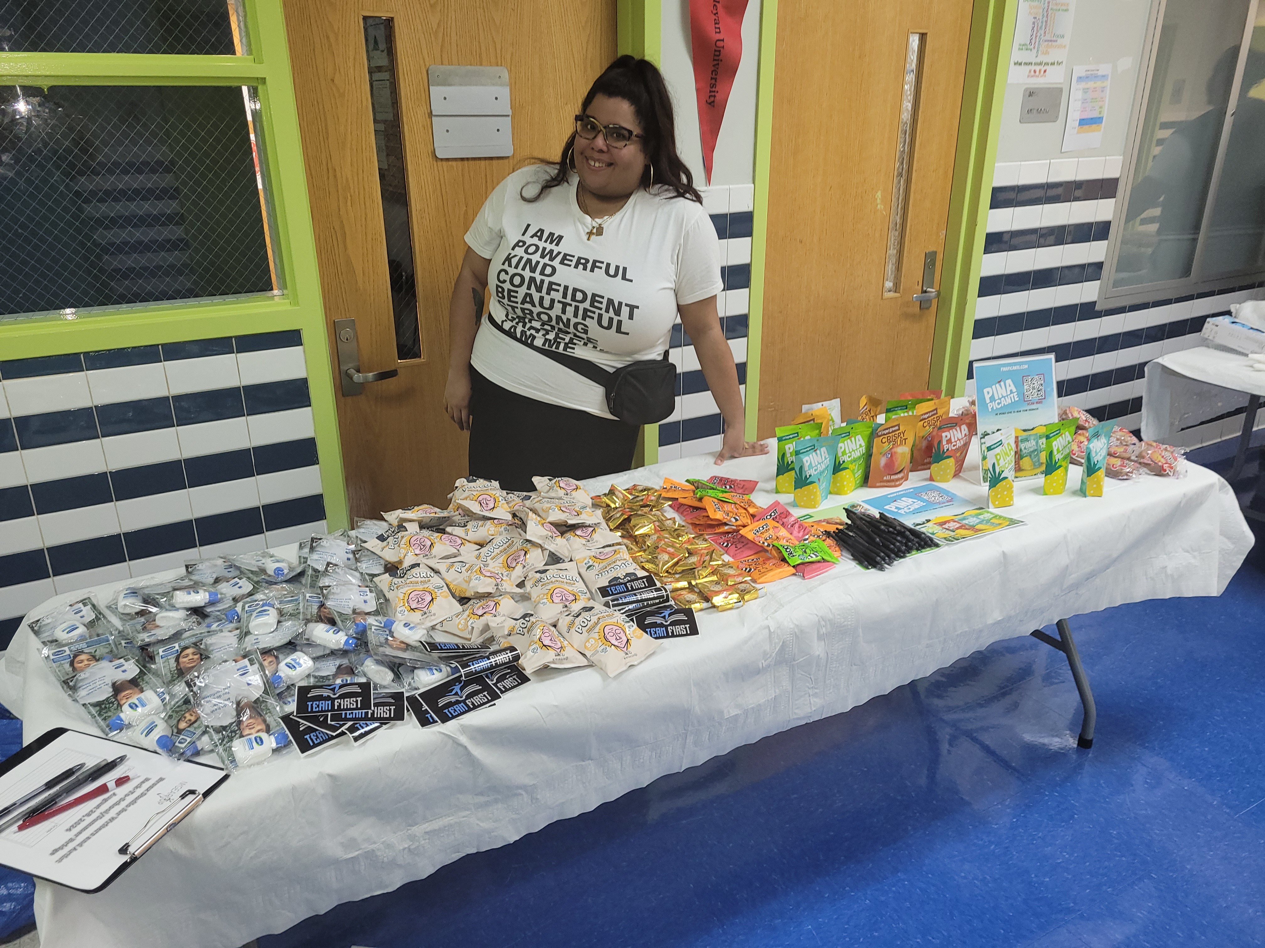 Woman standing behind a table with snacks and drinks, in a room with green and blue walls.