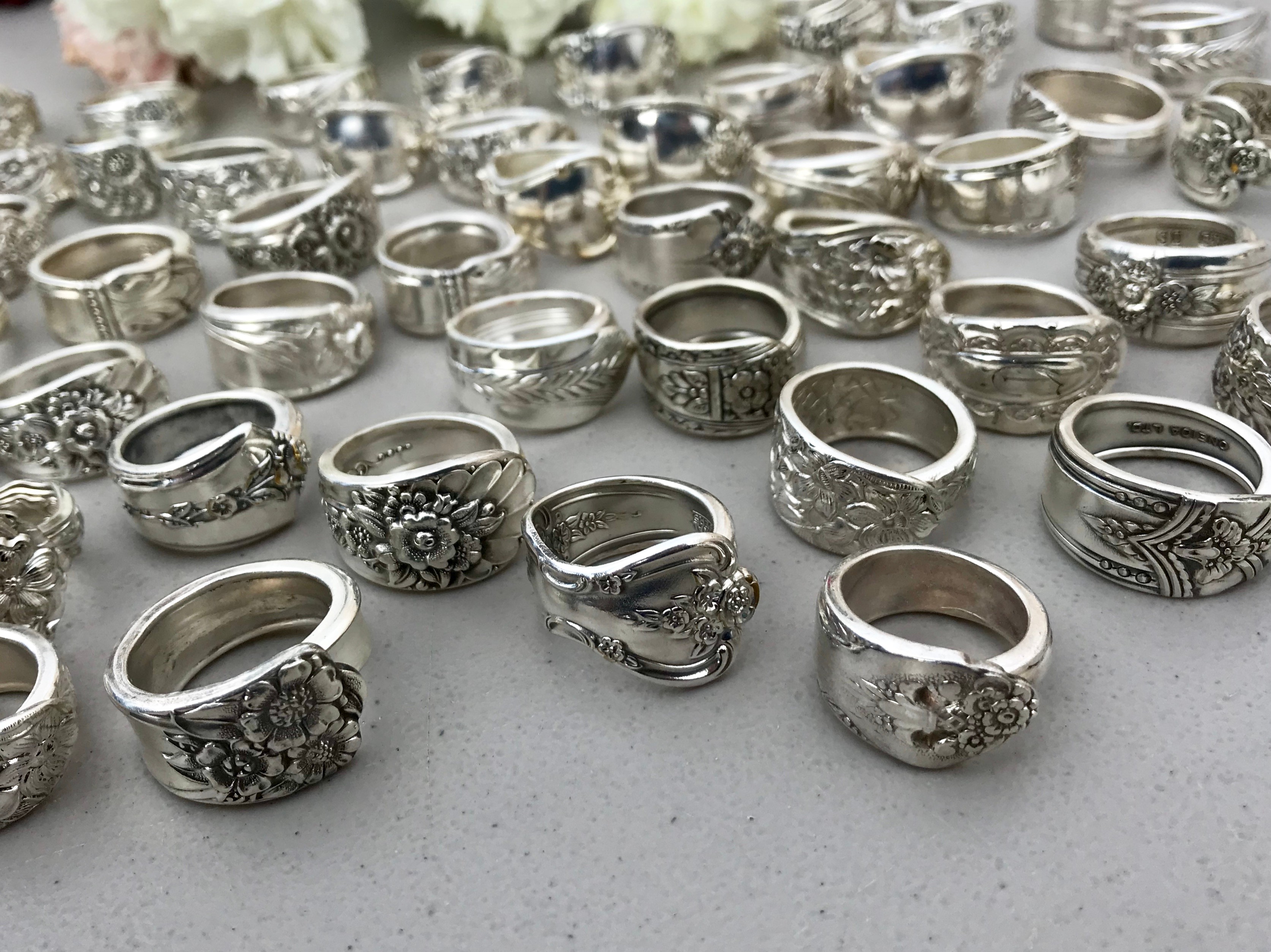 Collection of silver rings with various designs displayed on a flat surface.