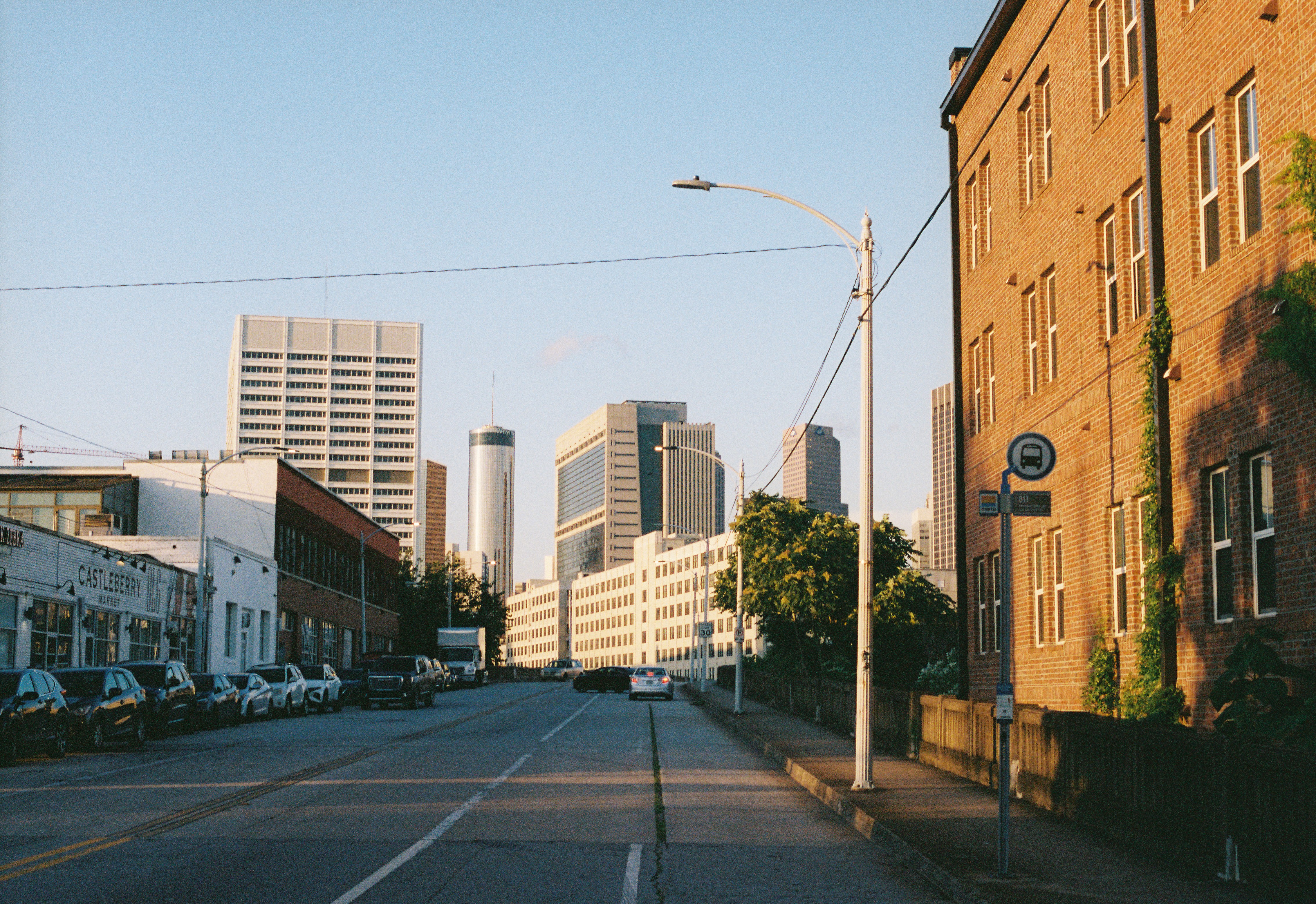 City street with buildings, parked cars, and a streetlight, under a clear sky.