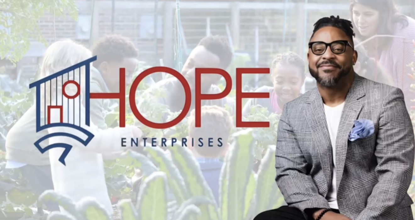 Man in gray suit smiling, background shows people and plants, logo with the word 'HOPE' and a building icon.