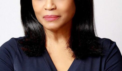 Woman with shoulder-length black hair wearing a dark blue top, looking at the camera with a neutral expression.