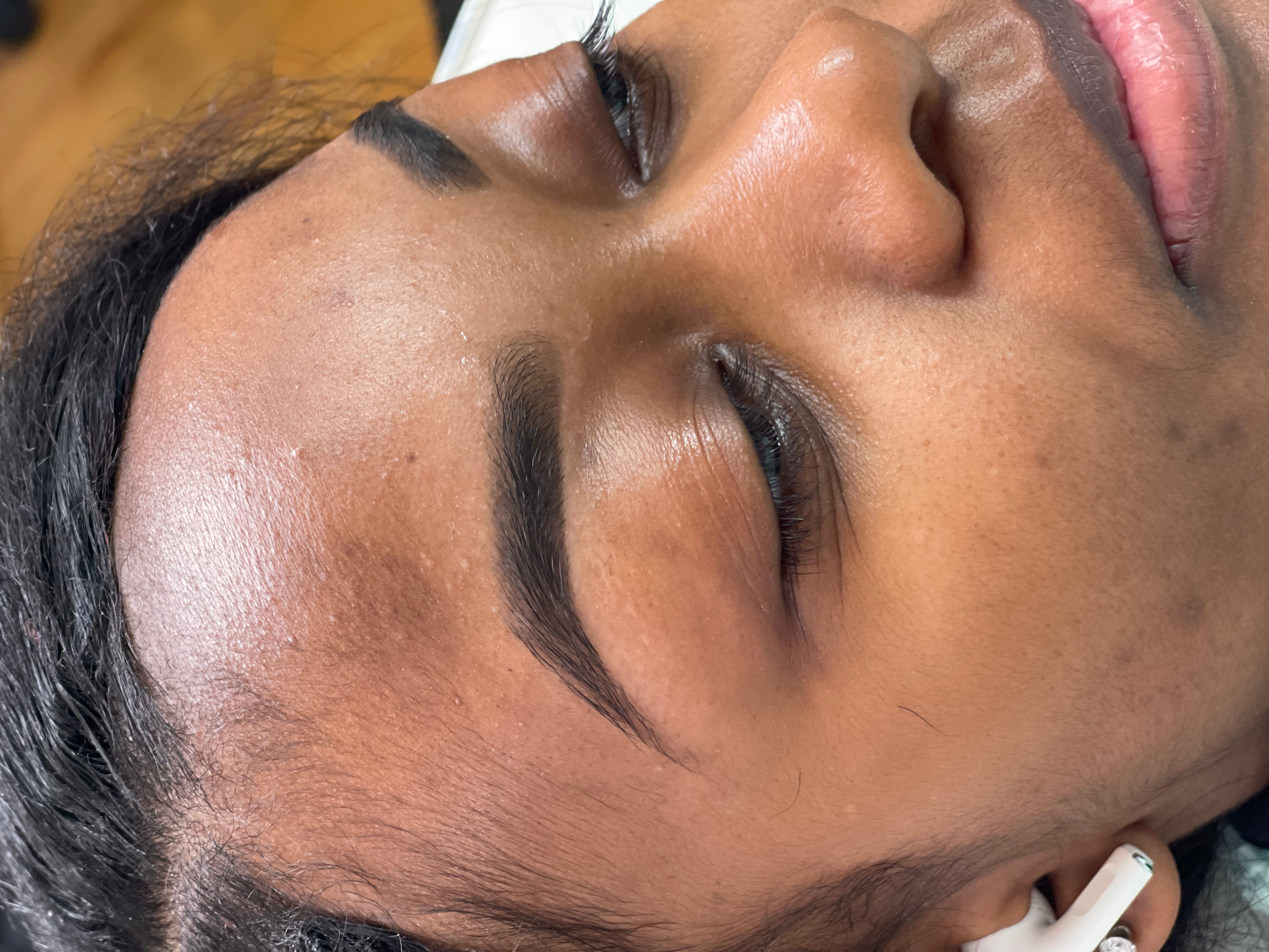Close-up of a woman's face with eyes closed, showing smooth skin and well-groomed eyebrows.