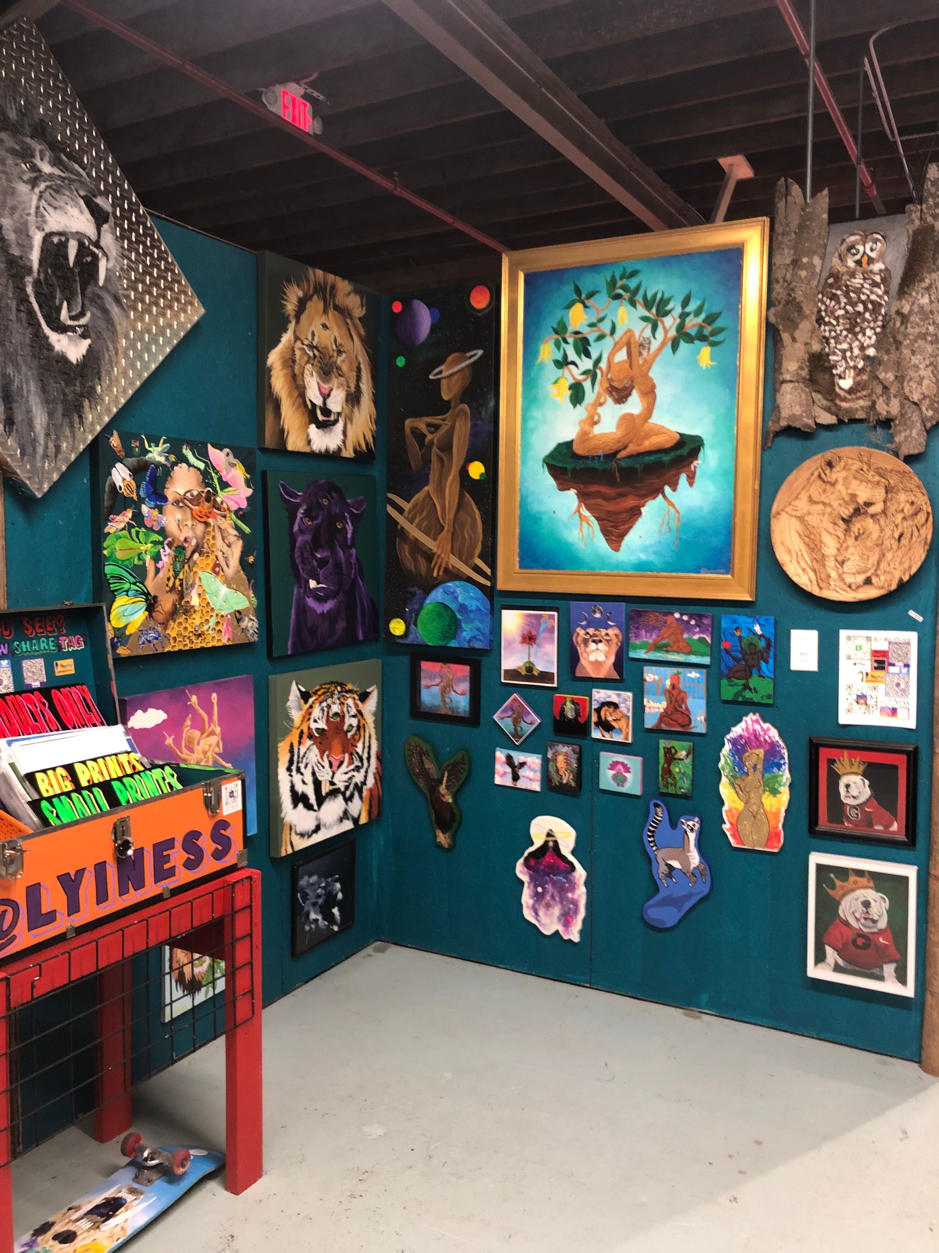 Gallery wall with framed artwork, paintings, and decorative items on a teal wall, with a red ladder nearby.