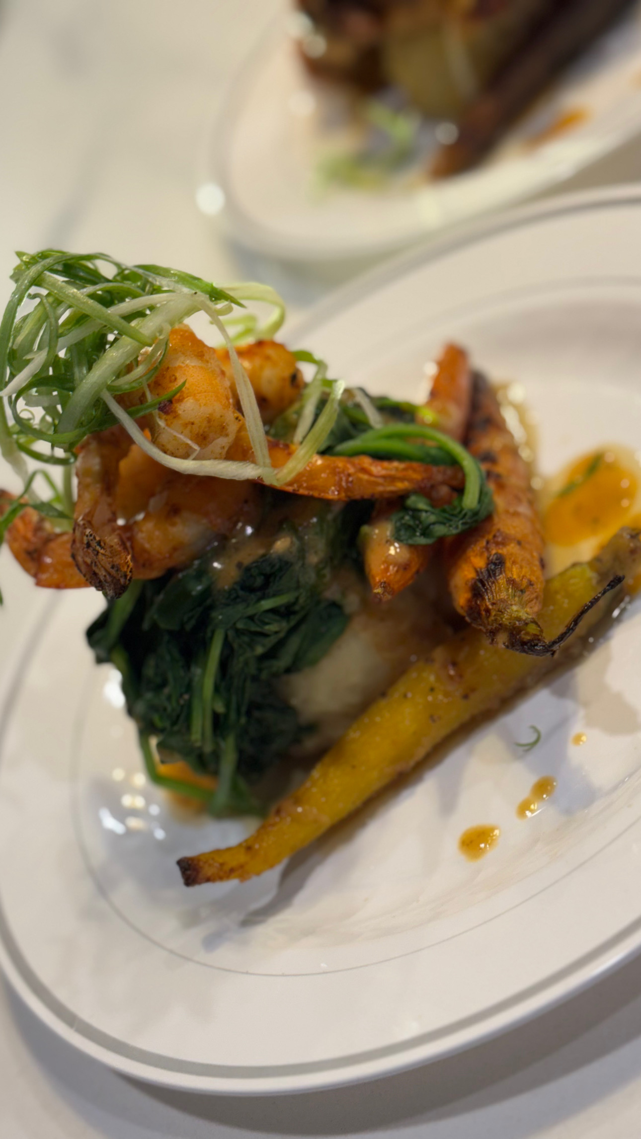 Plated dish with fried vegetables, greens, and garnishes on a white plate, with a blurred background.
