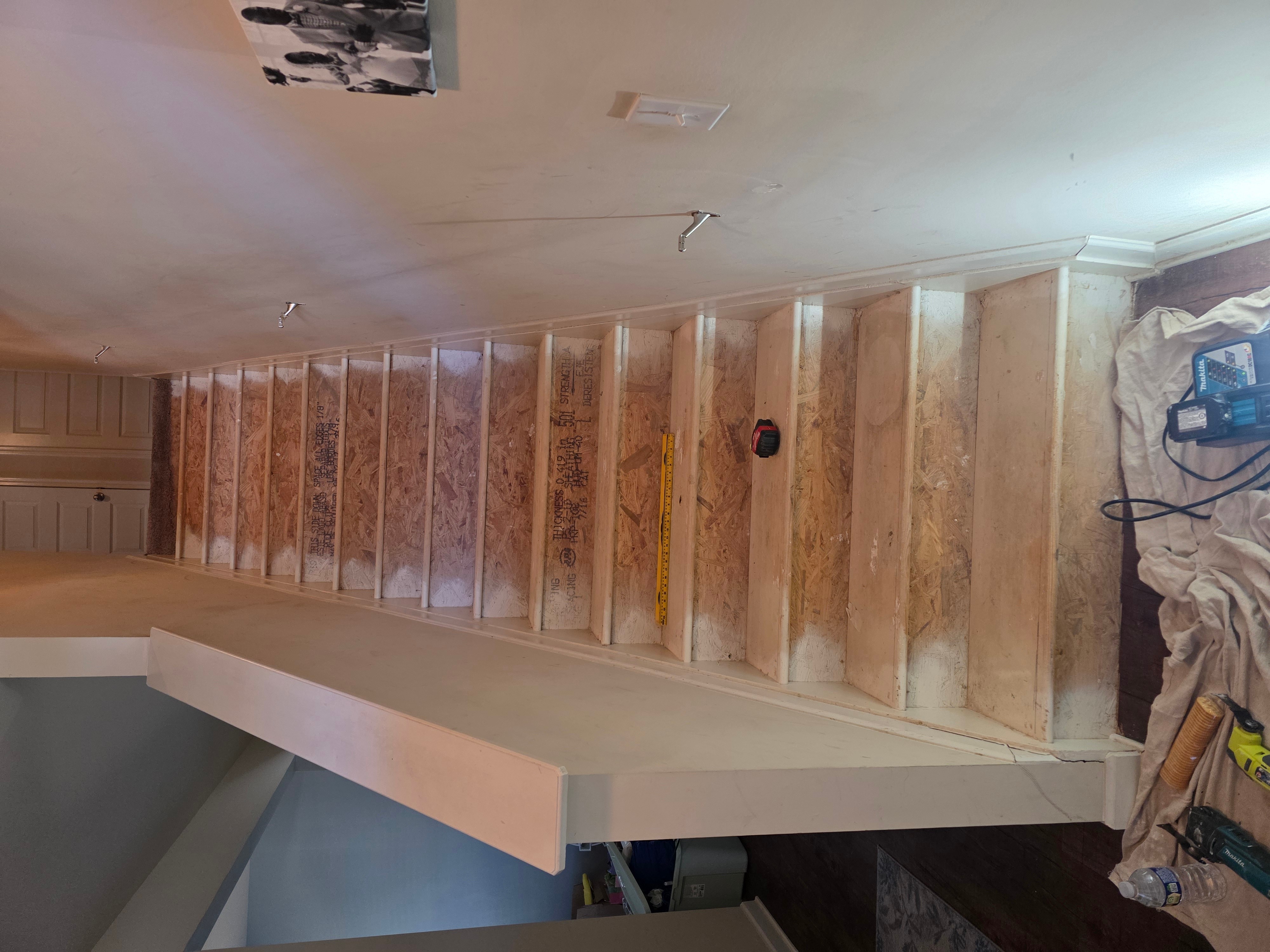 Wooden staircase with visible dust and tools on the side, leading upward in an indoor setting.