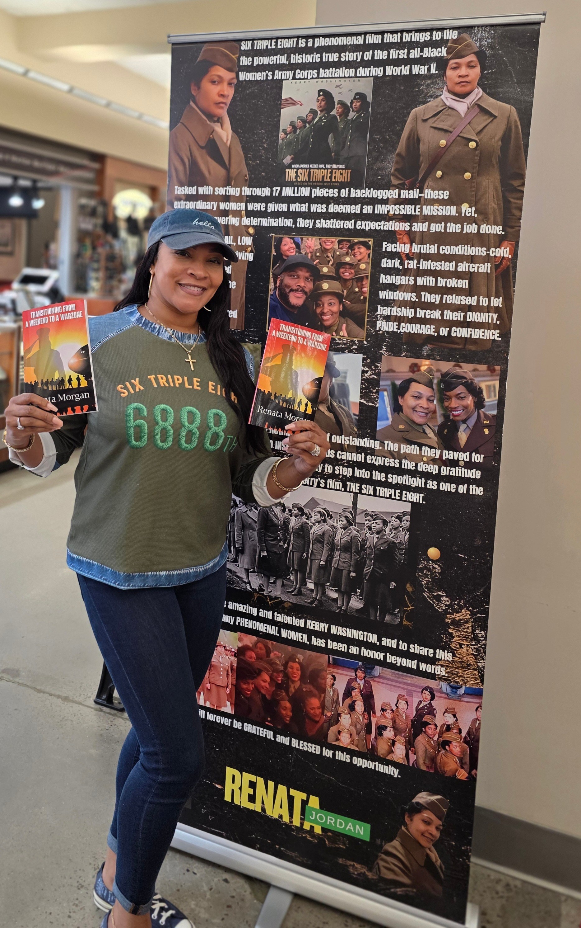 Woman holding a pamphlet and standing next to a large informational poster in a mall, smiling, wearing a cap and casual clothes.