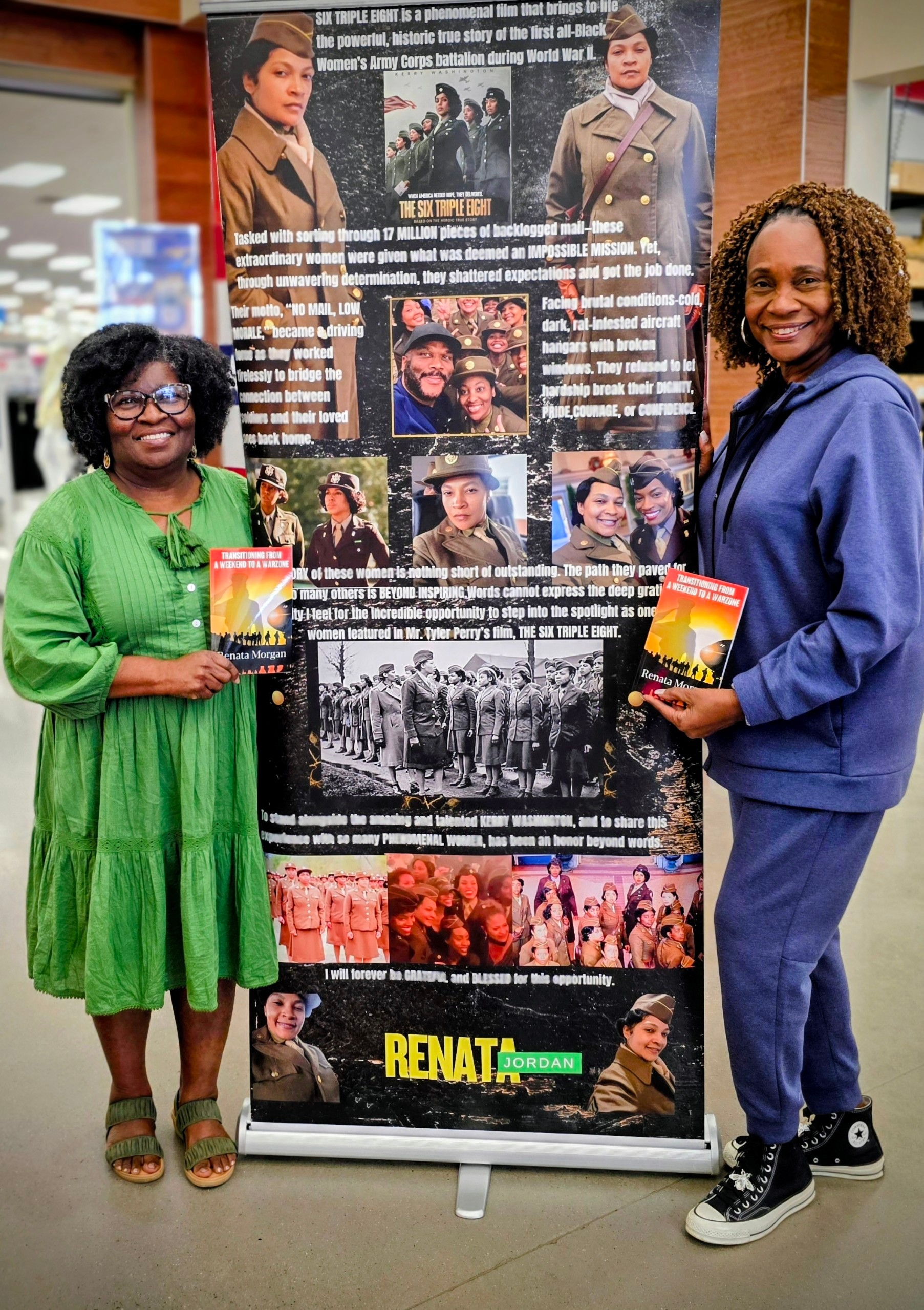 Two women stand beside a display board with historical photos and text, holding books, in an indoor setting.