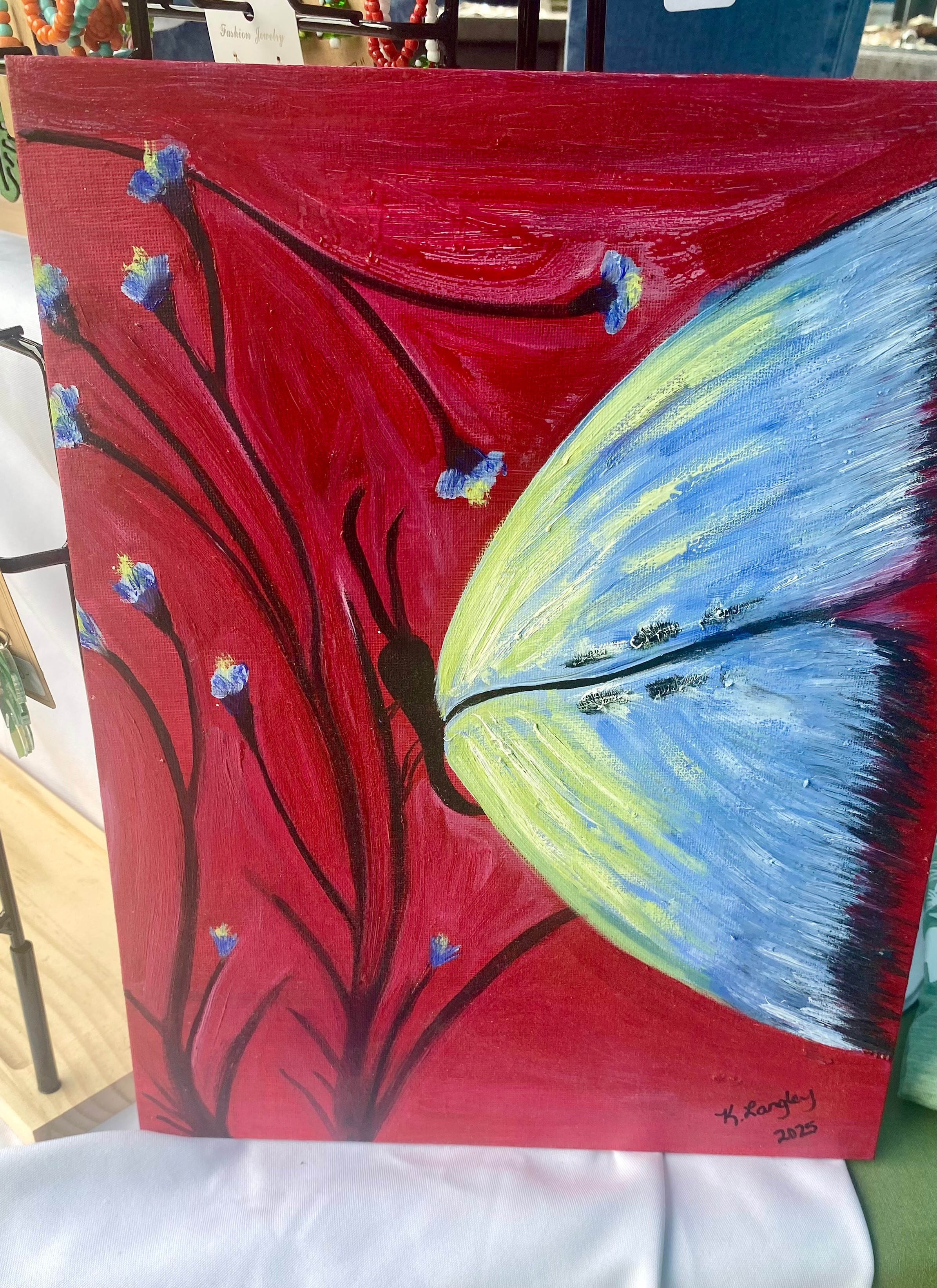 Close-up of a colorful butterfly with blue, yellow, and black wings on a red background with abstract black lines.