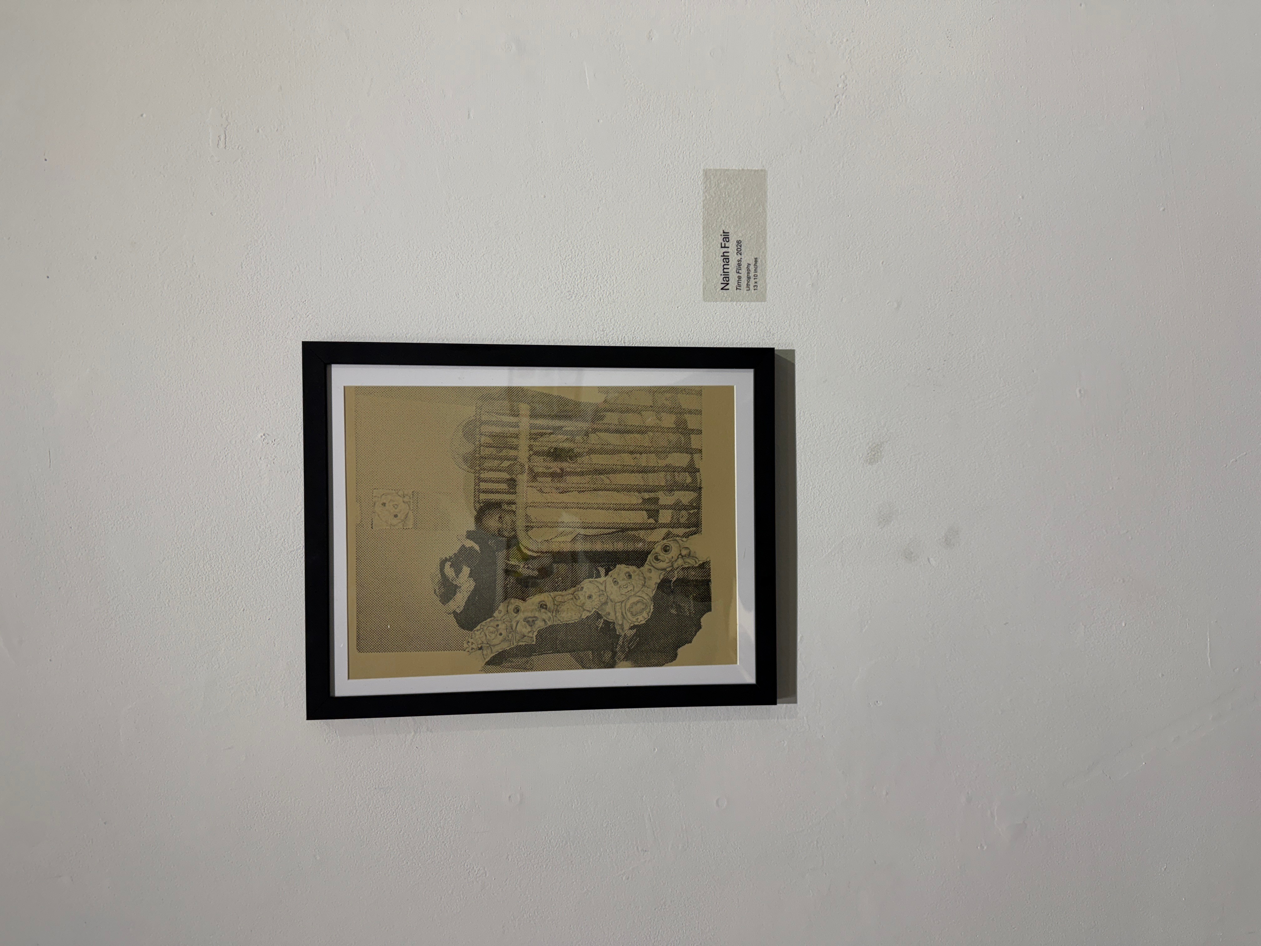 Framed artwork on a white wall, with a small label above it, featuring abstract shapes and lines.