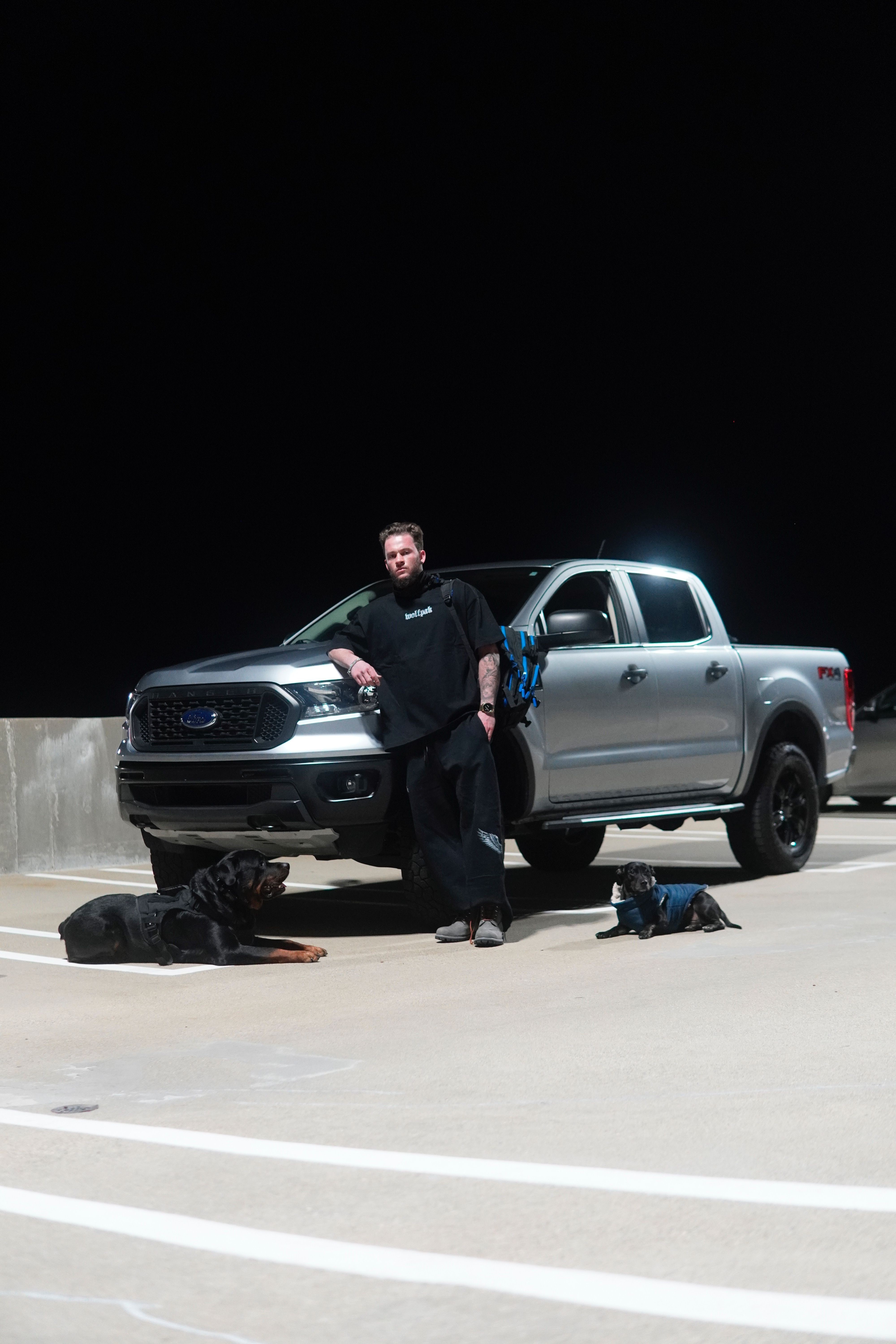 Person standing next to a silver pickup truck on a parking lot at night.