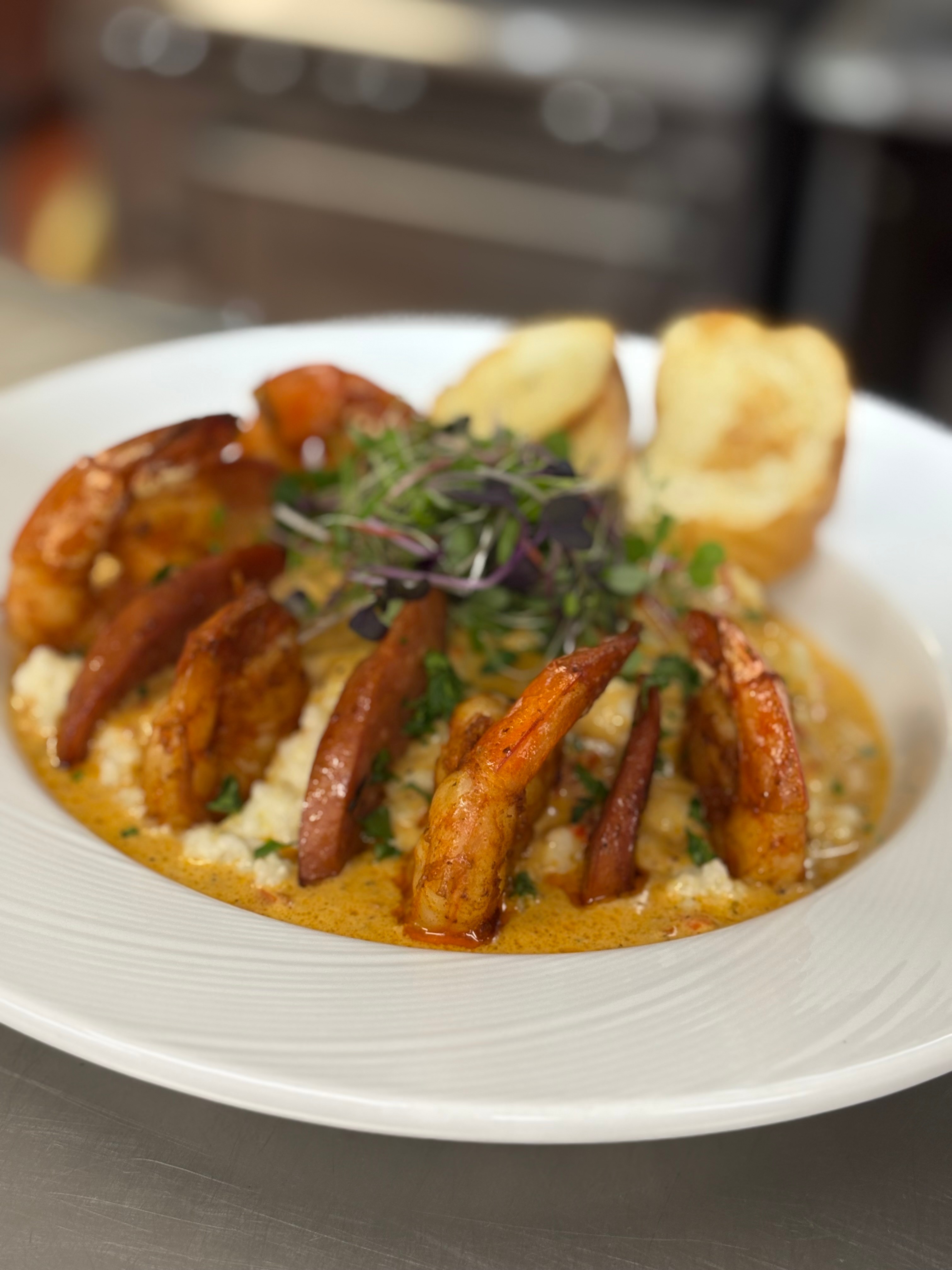 Plate with fried shrimp, garnished with herbs, accompanied by bread and sauce, on a white dish.