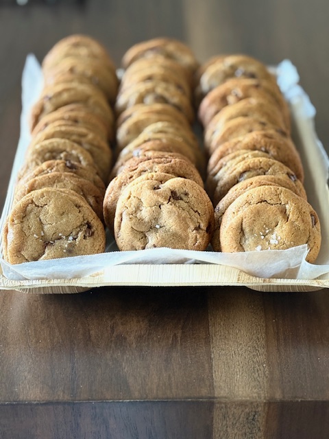 Three rows of cookies on a tray lined with paper, placed on a wooden surface.