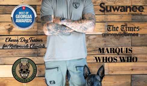 Man in gray shirt and cap with a black dog in front, wooden background with training-related text and logos.
