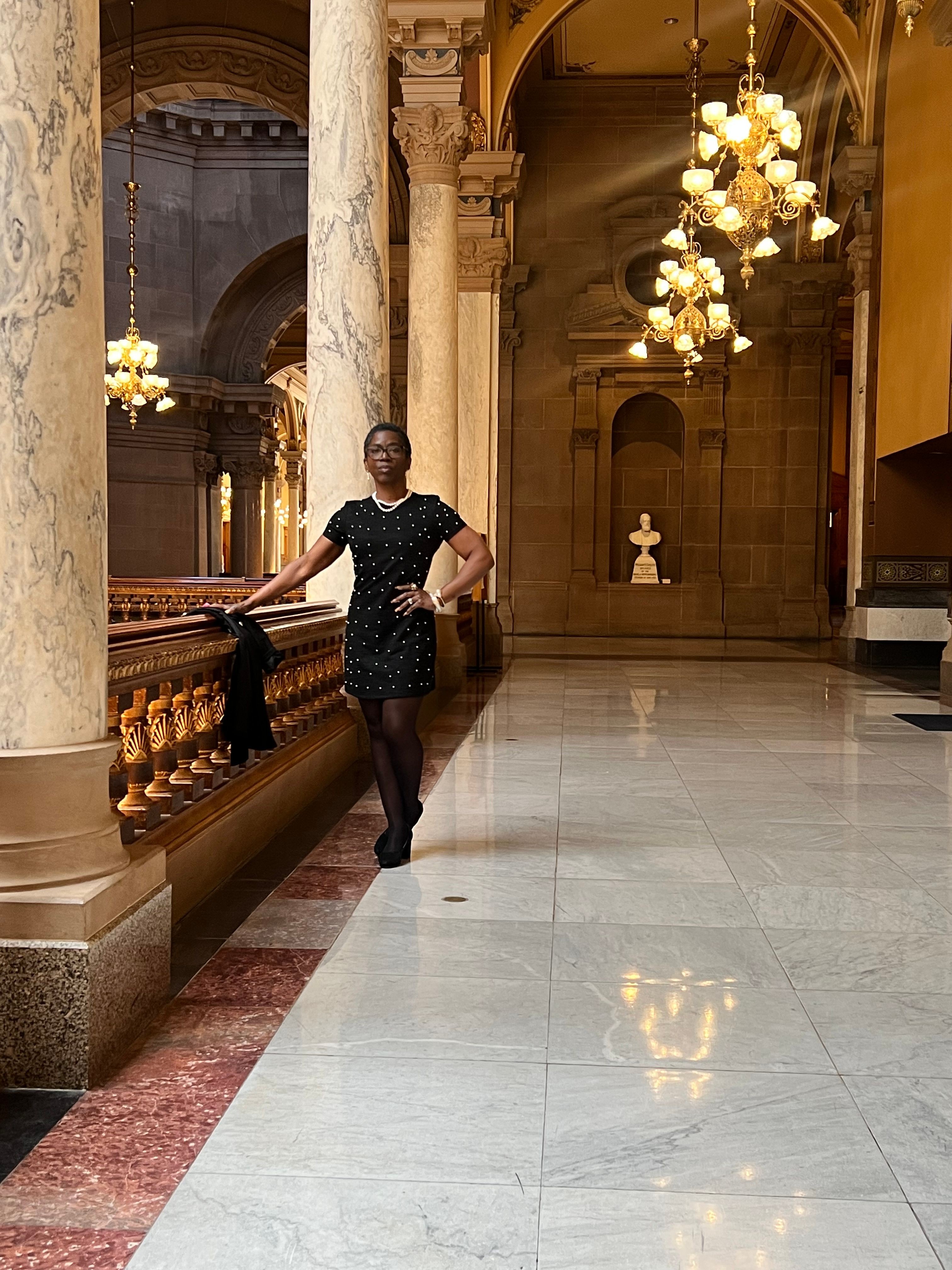 Person standing in a luxurious hotel lobby with marble floors and ornate lighting fixtures.