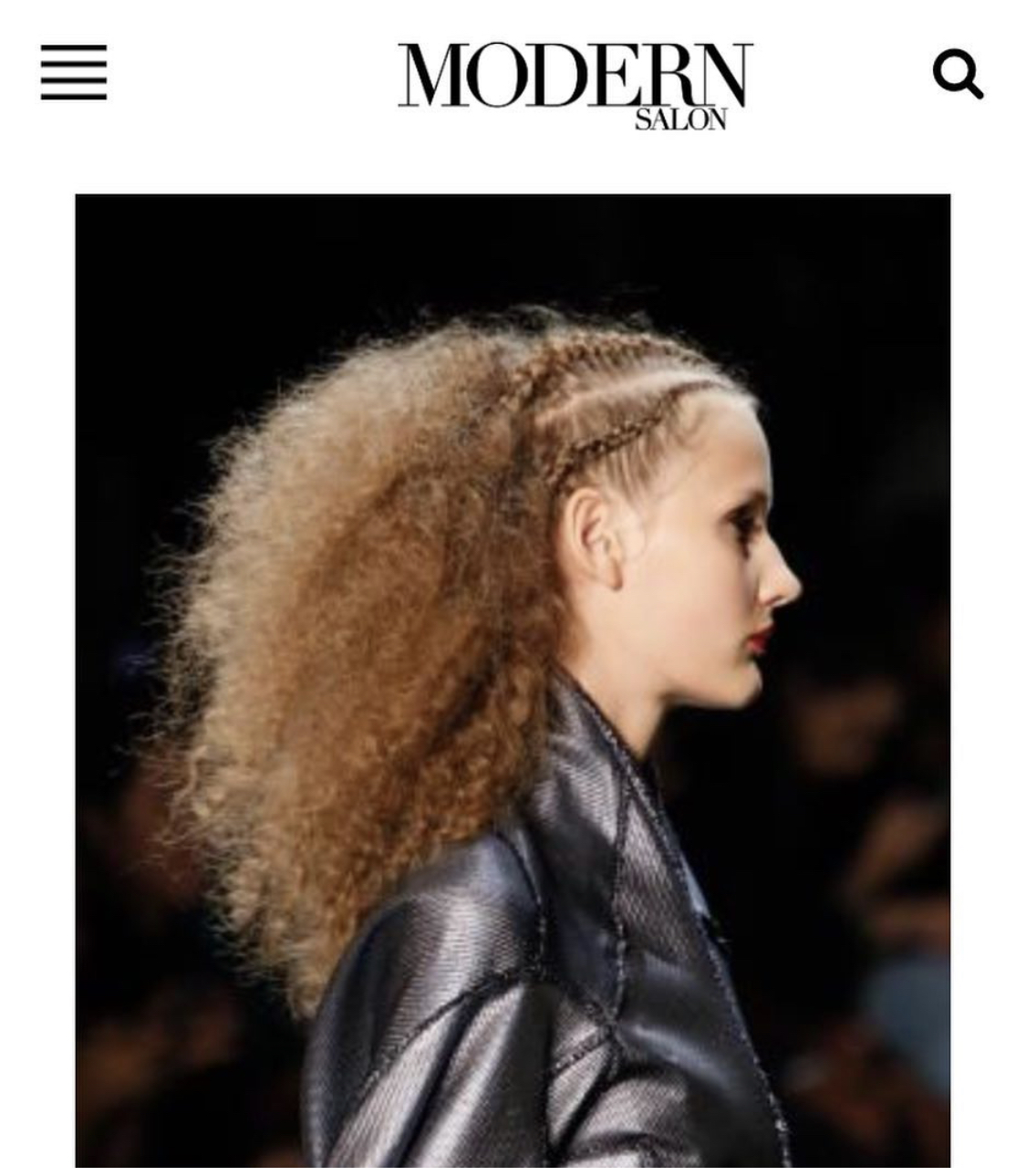 Side profile of a woman with curly hair and a leather jacket, on a dark background.