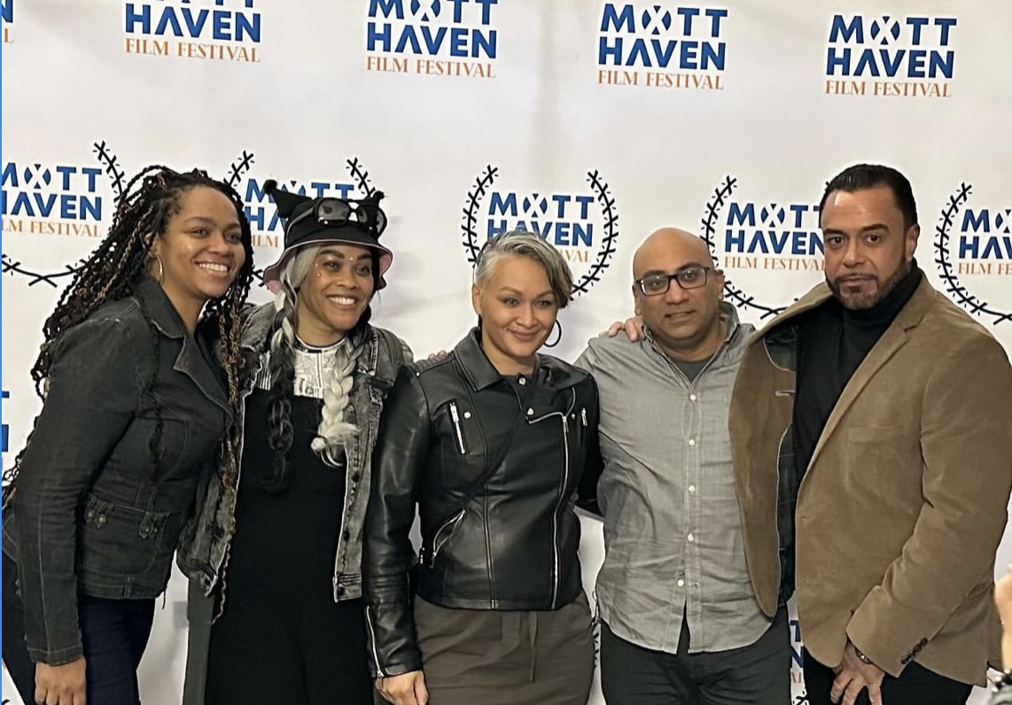 Five people standing together in front of a backdrop with 'Mott Haven Film Festival' logos, smiling for the photo.
