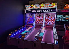 Three arcade ticket redemption machines with colorful graphics and a sign that says 'TO WIN 500 TICKETS'.