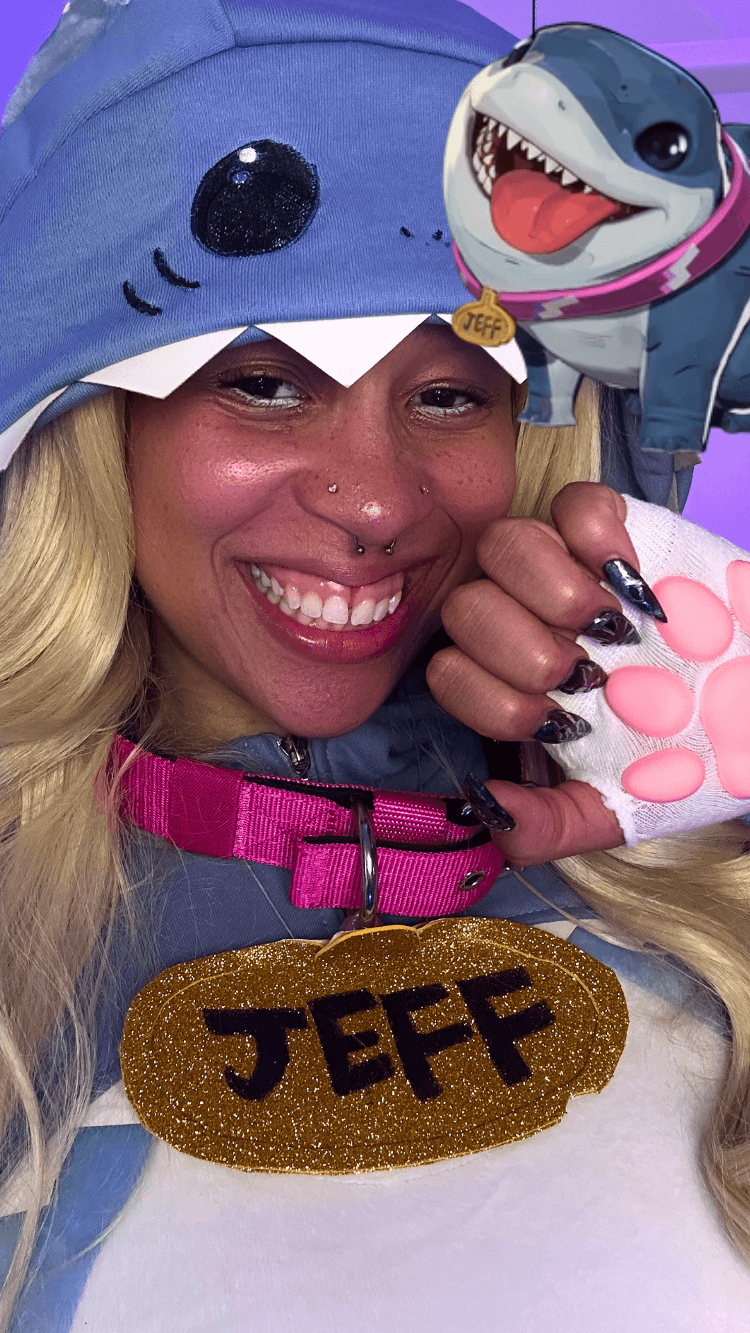 Person wearing a shark costume with a smiling face, holding a plush shark, and a name tag reading 'JEFF'.