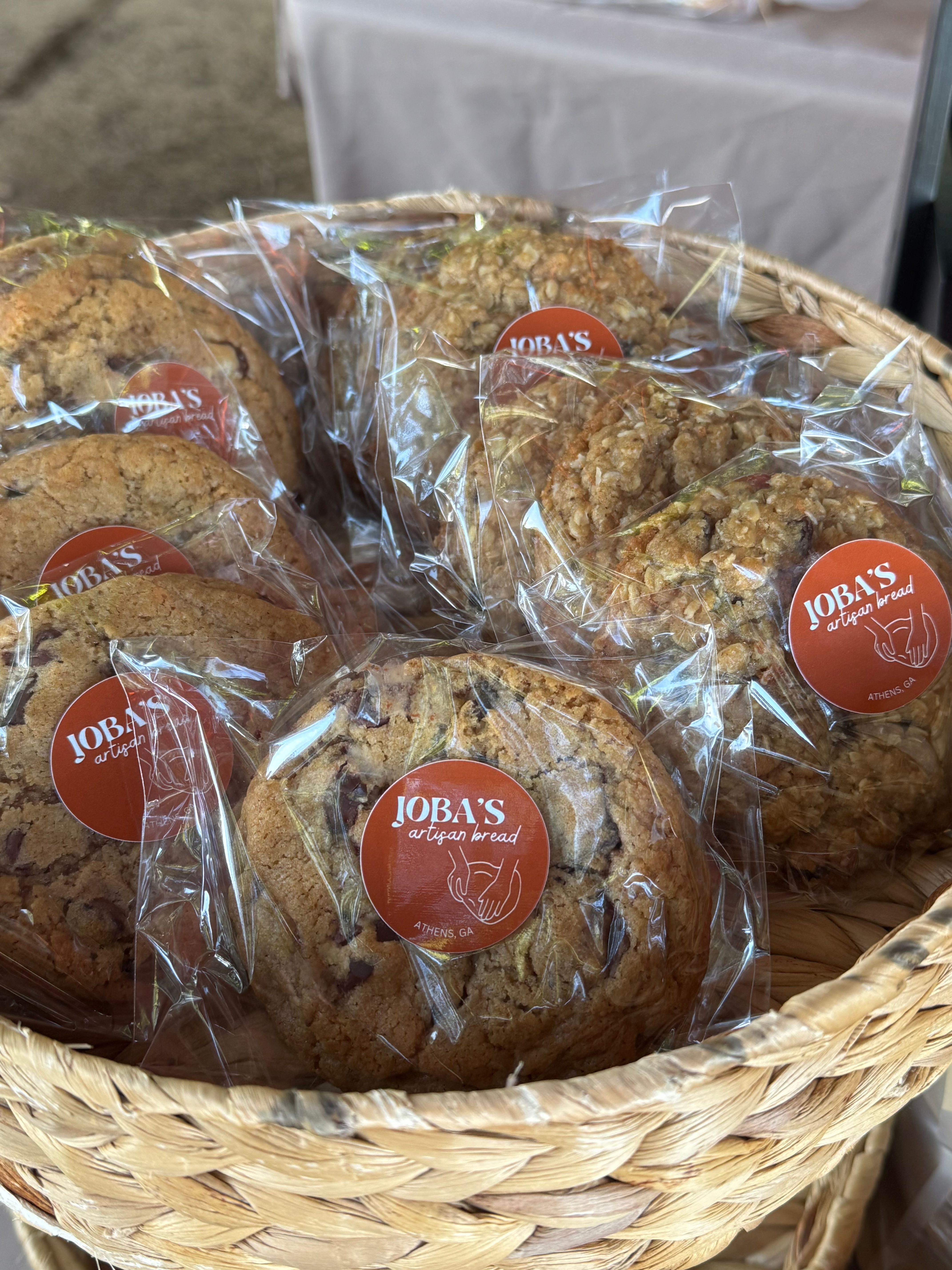 Cookies in clear plastic wrapping with red and white labels inside a woven basket.