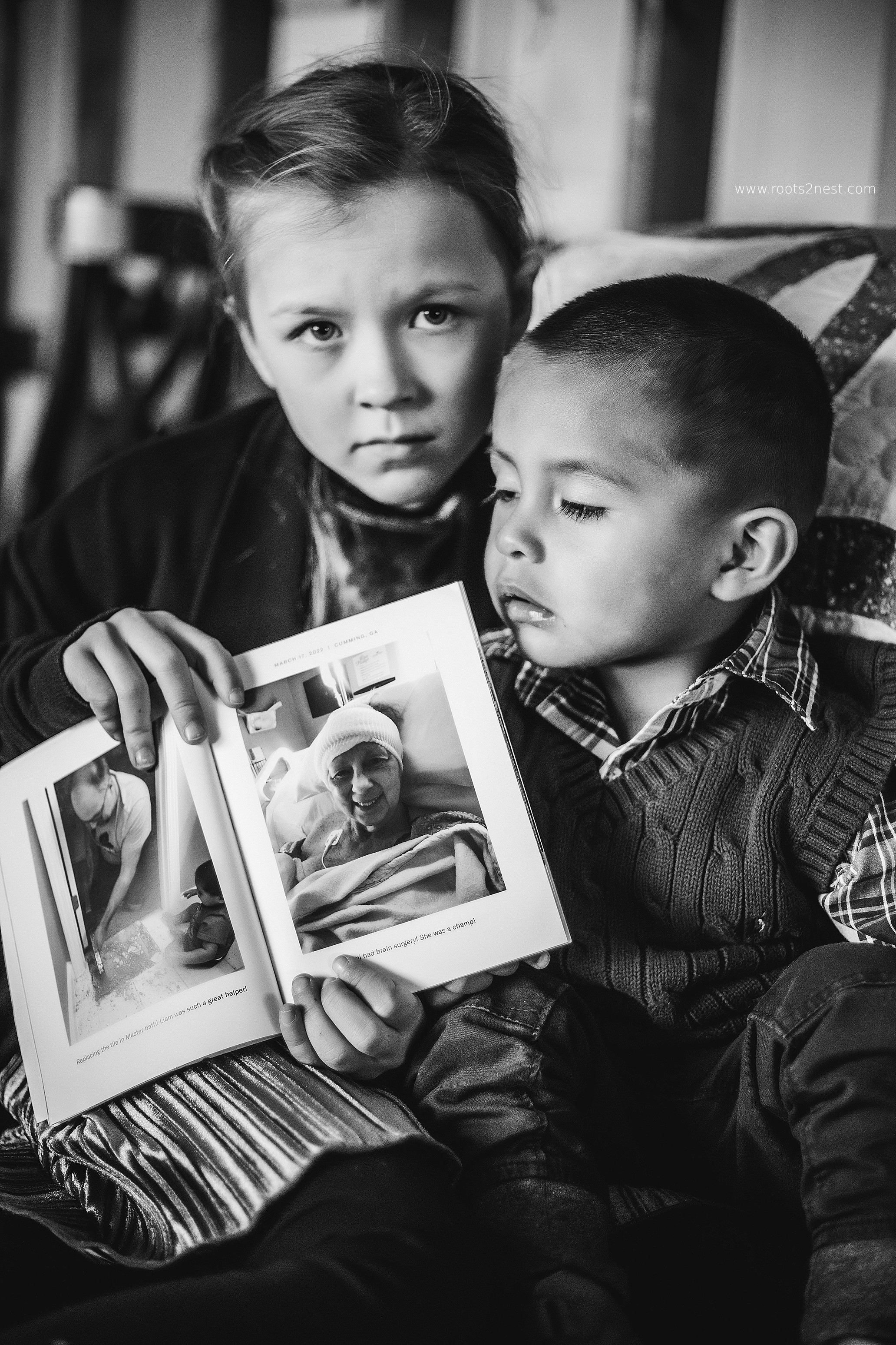Two children, one girl and one boy, look at a photo album together indoors.
