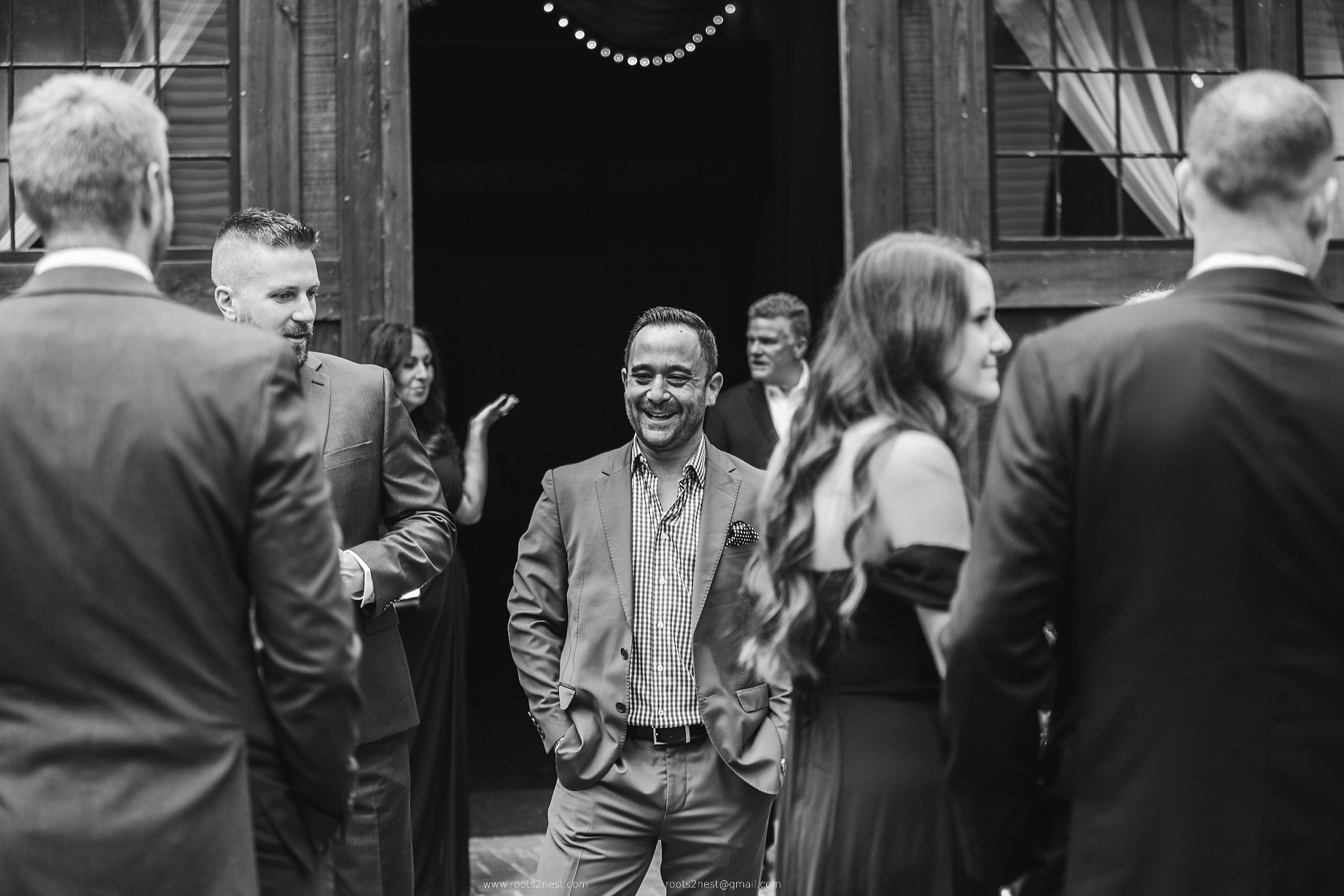 Group of people in formal attire socializing indoors, smiling and engaging with each other.